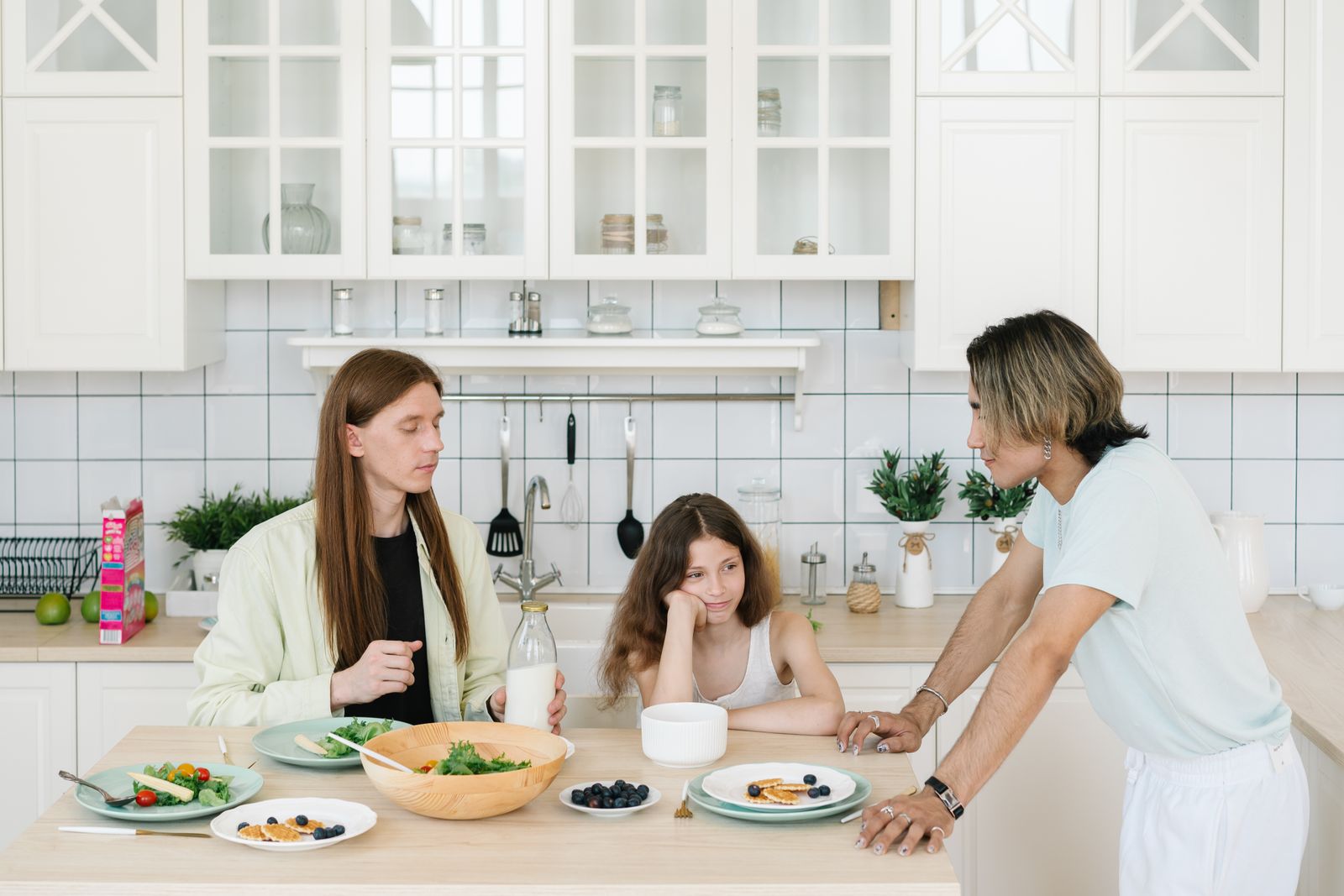 Gezin aan het ontbijt in een lichte keuken met de deur open